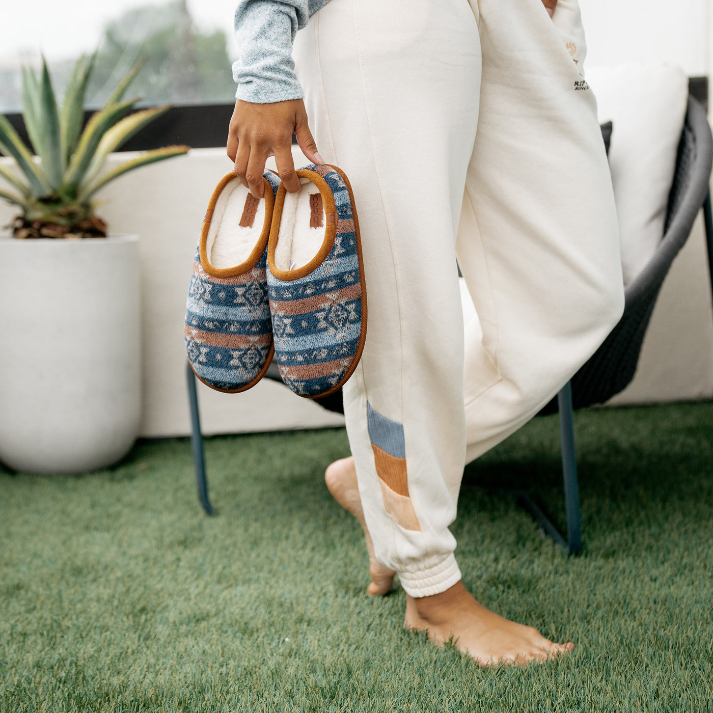 Model carrying the Cobian Supai chestnut on cozy turf balcony #color_chestnut