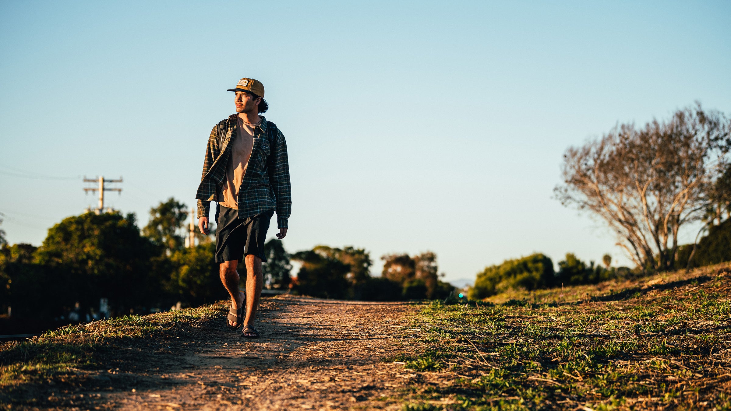 A man walking on a dirt trail wearing the Cobian Trestles Trek Slide