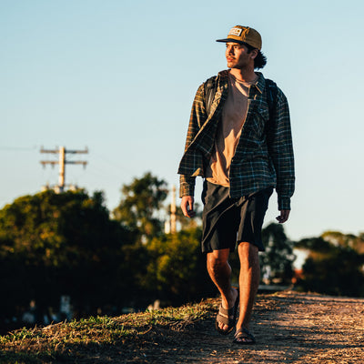 A man walking on a dirt trail wearing the Cobian Trestles Trek Slide #color_chocolate