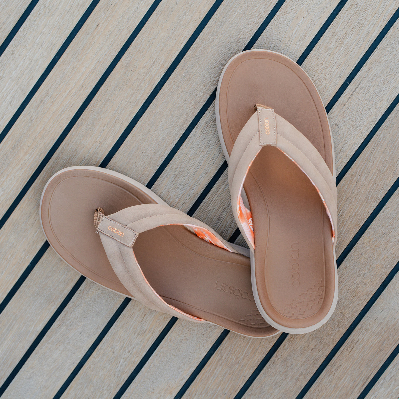 A close up of Cobian Darby Tan sandals on a boat deck #color_tan