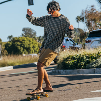 A man skateboarding in the street wearing the Cobian® Floater 2™ Mocha sandals #color_mocha