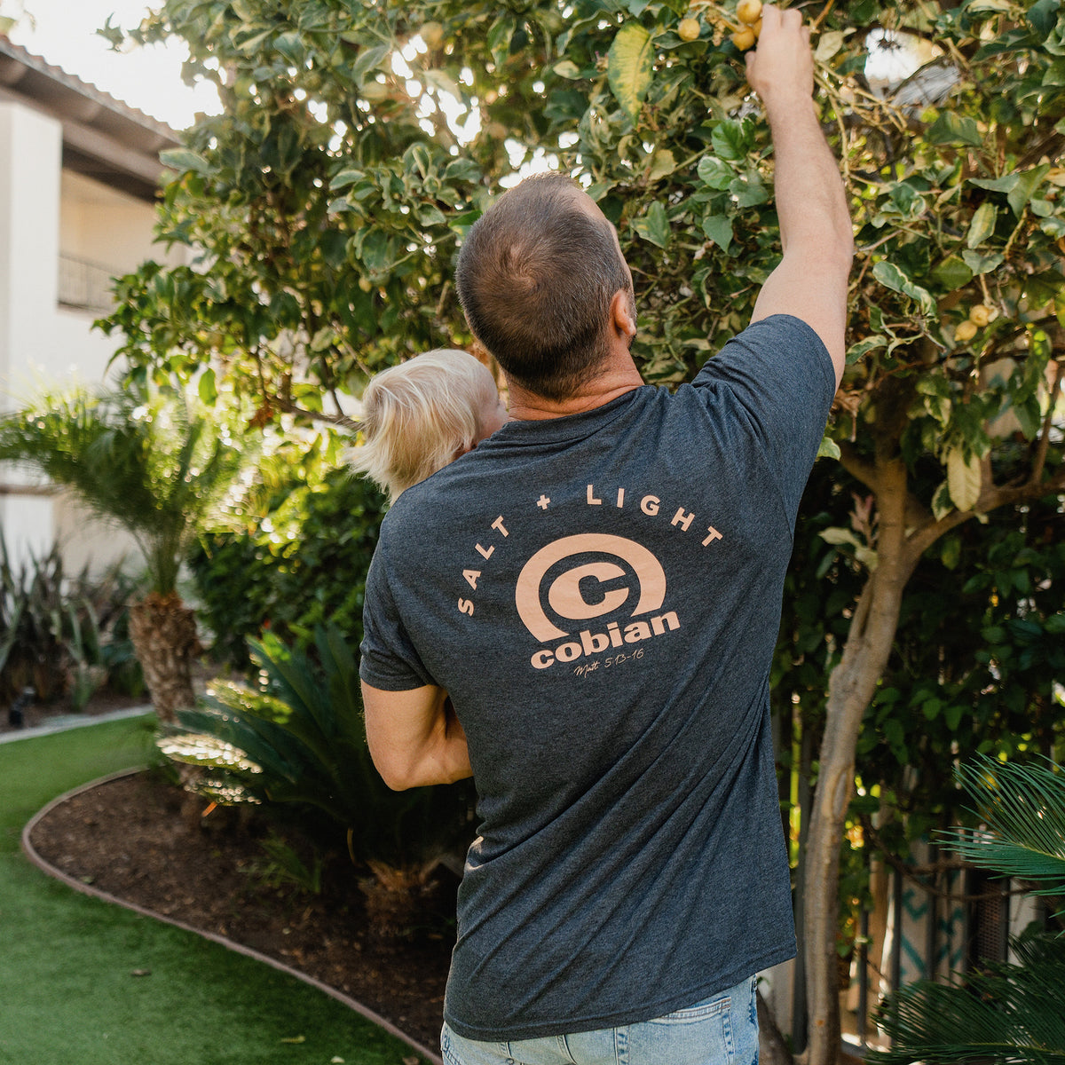 Adam Dirks wearing the Cobian Salt + Light Arc T-Shirt. Back detail.  #color_charcoal