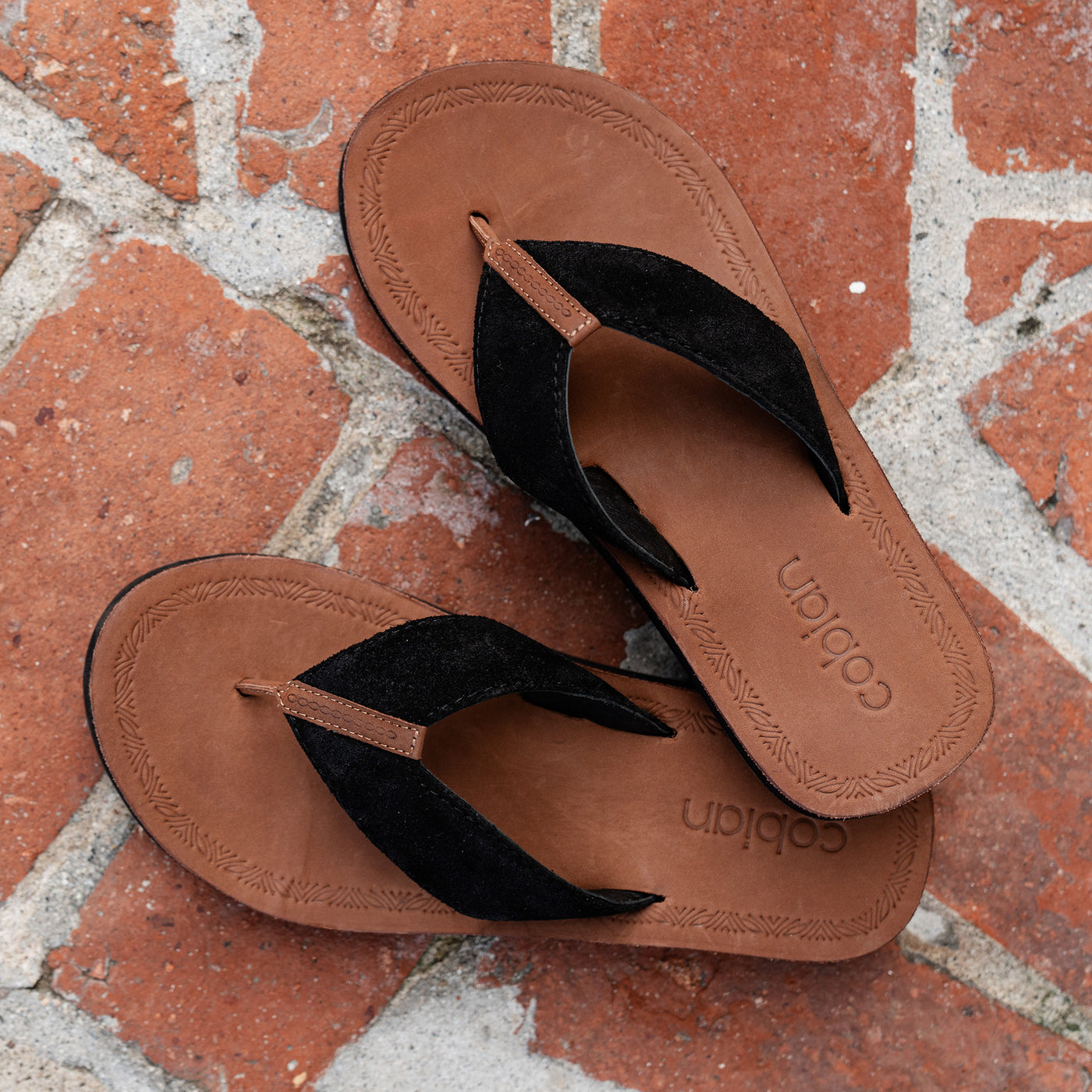 Detail of Cobian Campo Del Sol Paloma Black leather sandals on brick background #color_black